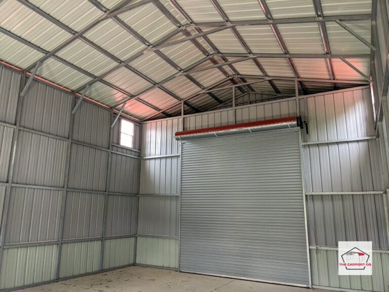 Interior of tall metal garage that has vertical siding and a vertical roof with a 12x14 roll up door installed on one end.