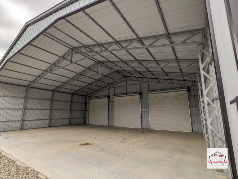 Corner interior of commercial truss wide span pre-engineered metal building (PEMB) with vertical siding and three 12x12 roll up doors.