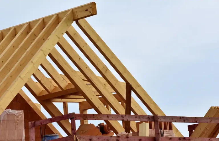 Example photo of wood framing in A-frame configuration. The structure appears to be a house. The photo is used to showcase the benefits and drawbacks of metal vs wood framing.