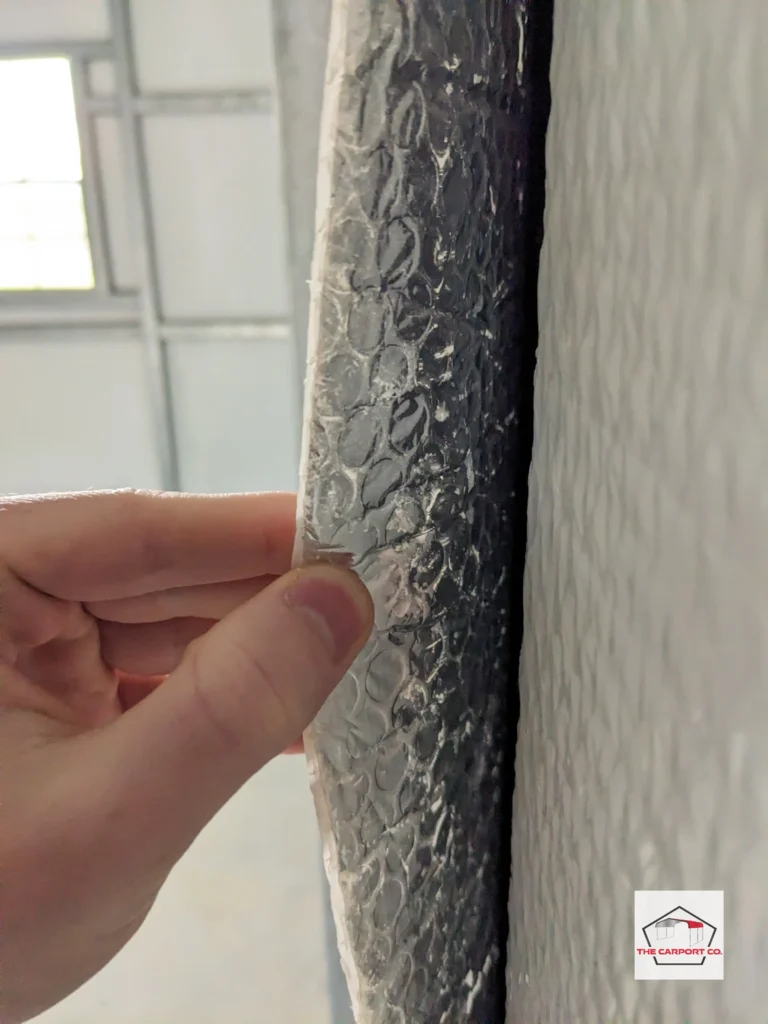 Close up of reflective foil double bubble insulation with both sides visible as the reflective side is being opened with a hand. Reflective foil is a type of carport insulation that prevents metal carports and metal buildings from sweating.