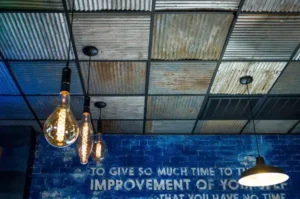 Photo of suspended ceiling in prefabricated metal building made from tin. It's being used to hide the electrical work from the lights hanging and to improve insulation of the structure. Drop ceilings in metal buildings are great investments.