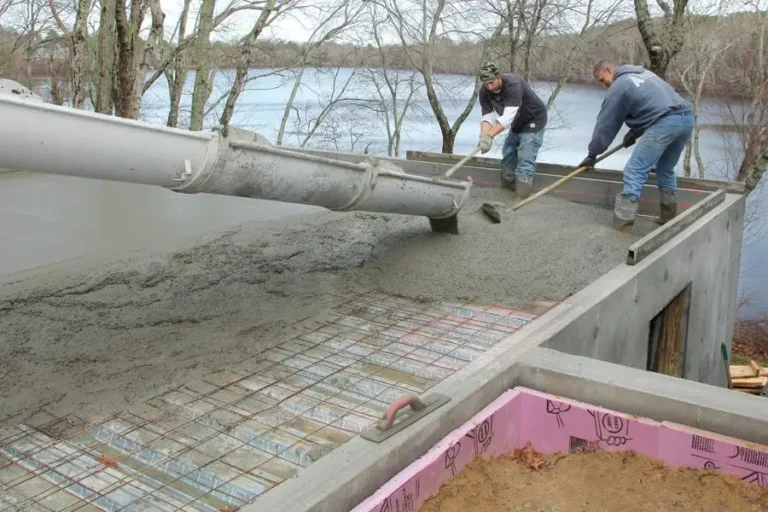Two men pouring concrete for a concrete slab foundation that a future metal garage building or carport can sit on top of.